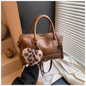 Détail d'un sac Boston marron en similicuir plissé avec un charme de cœur léopard