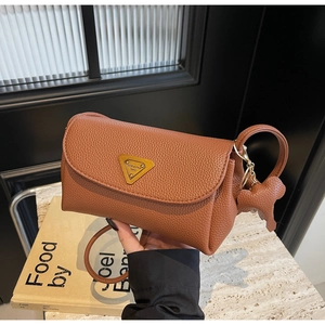 Detail of a brown lychee pattern leather shoulder bag with gold metal triangular emblem