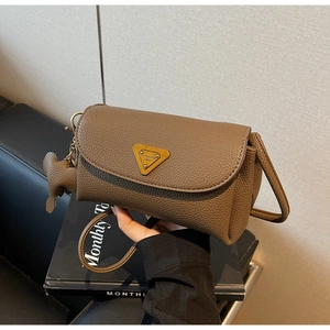 Close-up of brown litchi pattern leather texture and golden triangle logo on the bag
