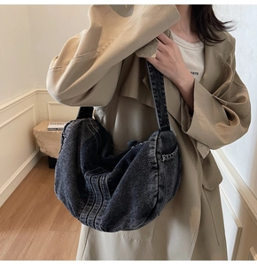 Detail of grey washed denim hobo bag showing large capacity and textured stitching