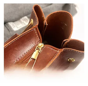 Macro detail of brown leather bag showing polished gold zipper and white contrast stitching