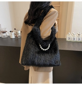 Detail of black faux fur shoulder bag with decorative white pearls held by a model