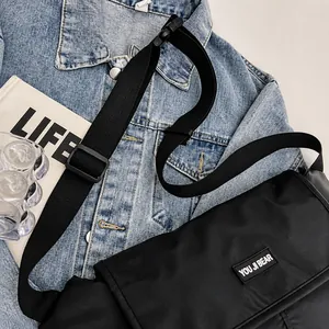 Detail van verstelbare geweven riem op een zwarte waterdichte crossbodytas op denim