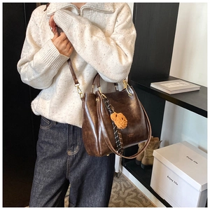 Detail of dark brown vintage bucket bag with adjustable strap and orange fur ball charm