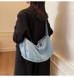 Detail of blue denim tote bag showing side flap pocket and soft vertical stitching fabric