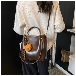 Dark brown retro bucket bag with cute bear charm shown in a lifestyle model shot