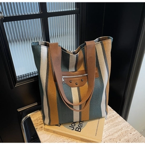 Detailed texture of multi-colored striped woven tote bag with leather pocket and rivets