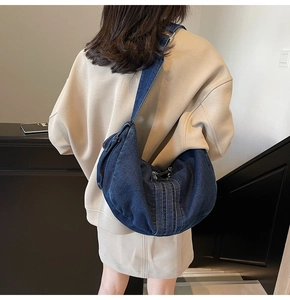 Detail view of large denim crescent shoulder bag styled with casual oversized hoodie