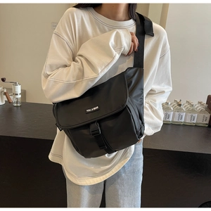 Close-up of a black retro messenger bag with a buckle and sporty crossbody strap