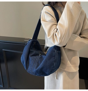 Detail shot of navy denim crescent hobo bag with decorative vertical stitching and wide strap