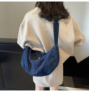 Detail of blue denim hobo bag showing adjustable wide shoulder strap and white contrast stitching