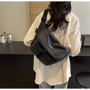 Detailed view of a black large capacity vintage messenger bag worn cross-body style