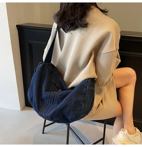Detailed view of deep blue denim crossbody tote bag with stitching and zipper details