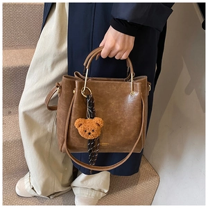 Detail of vintage brown tote bag with metal ring handle, charm, and silk scarf detail