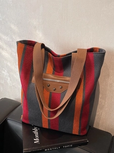 Vertical striped canvas tote bag with leather rivet details in red, orange and grey