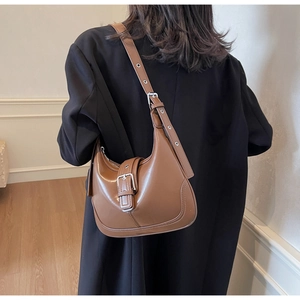 Borsa hobo in pelle marrone indossata con un blazer nero e dettagli della tracolla