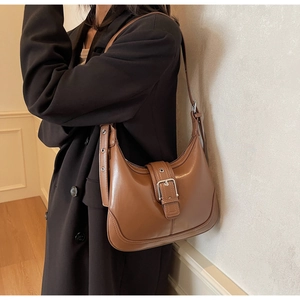 Borsa hobo a mezzaluna marrone con fibbia argentata indossata su un blazer nero