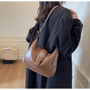 Dettaglio della borsa sottobraccio in pelle marrone scuro con fibbia in metallo sulla tracolla