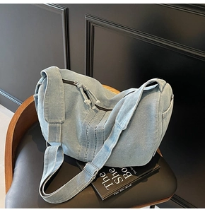 Detail of light blue denim hobo bag showing adjustable strap and silver metal buckle