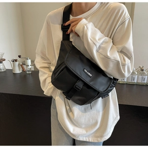 Close-up of black messenger bag featuring buckle closure and adjustable nylon shoulder strap