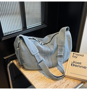 Detailed view of light blue hobo denim bag with vertical seams and adjustable strap