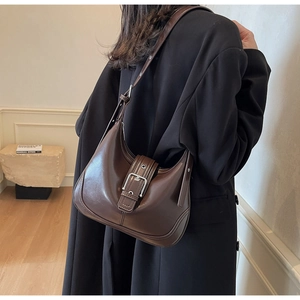 Borsa a spalla a mezzaluna marrone scuro con fibbia argento su cappotto nero