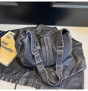 Detail of black washed denim crossbody bag with stripe texture on leather background