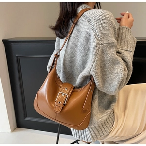 Dettaglio borsa a spalla vintage marrone con fibbia argento e tracolla su una modella