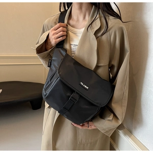 Detail of black messenger bag with adjustable buckle and functional zipper pocket