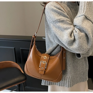 Borsa a spalla a mezzaluna in pelle marrone con fibbia argentata indossata da modella