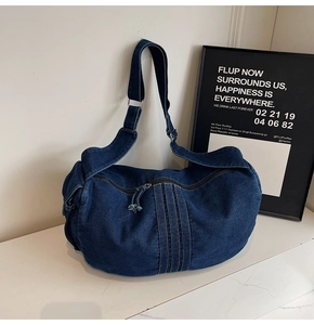Detailed macro shot of dark blue denim crescent bag with vertical stitching and silver buckle