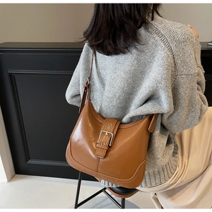 Borsa hobo in pelle color caramello indossata da una modella con un maglione grigio