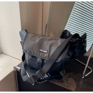 Detail view of large capacity black messenger bag with plastic buckle and logo