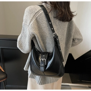 Vista laterale di una borsa hobo nera opaca con tracolla regolabile su una modella