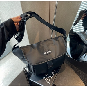 Detail of black nylon messenger bag featuring flap closure and adjustable strap