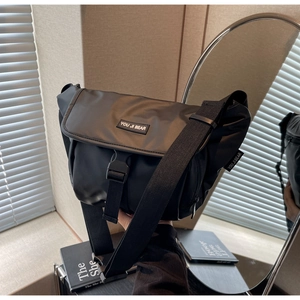 Detail of black matte nylon messenger bag featuring wide strap and large buckle closure