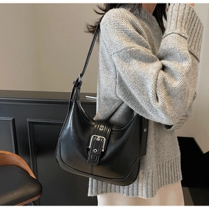 Vista laterale della borsa hobo nera con fibbia in metallo argento indossata da modella