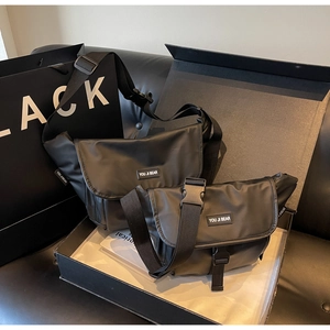 Macro shot of two black waterproof nylon messenger bags with buckles in a gift box