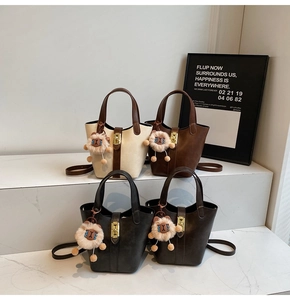 Array of bucket bags in beige, brown, and black with plush lion charms and crossbody straps