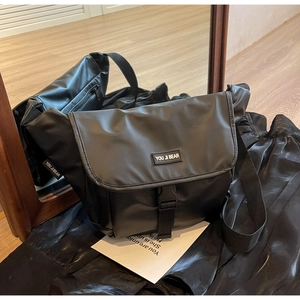 Detail view of black canvas dumpling bag with quick-release buckle and side brand label