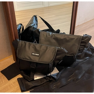 Detail of matte black messenger bag showing buckle closure and adjustable strap