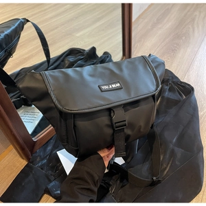 Detail shot of the black nylon messenger bag featuring a buckle closure and logo strap