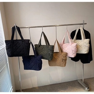 Quilted tote bags in various colors hanging on a rack with side zipper detail