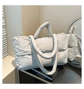 Close-up of ivory quilted puffer tote bag with glossy finish and puffy handles