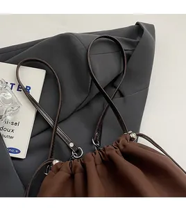 Detail of a brown drawstring bucket bag with silver metal buckles and matte fabric texture