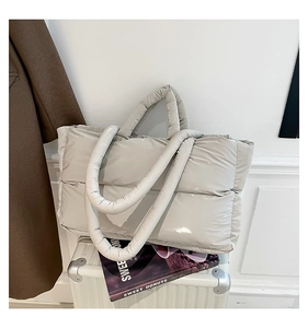 Detail of glossy quilted puffer tote bag in light grey with soft padded handles