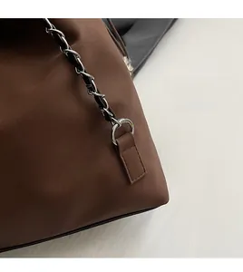 Close-up of brown leather bag with silver metal chain strap and detailed stitching
