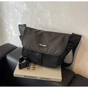 Detailed side view of a black waterproof messenger bag on a sleek leather sofa
