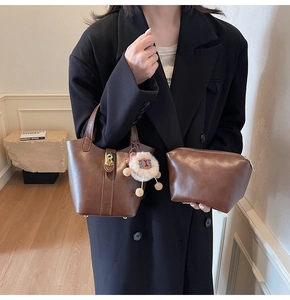 Brown leather bucket bag with inner pouch and plush charm worn with a black blazer