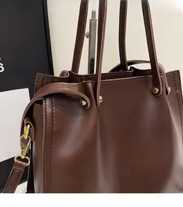 Close-up of dark brown tote bag showing leather texture and gold hardware details